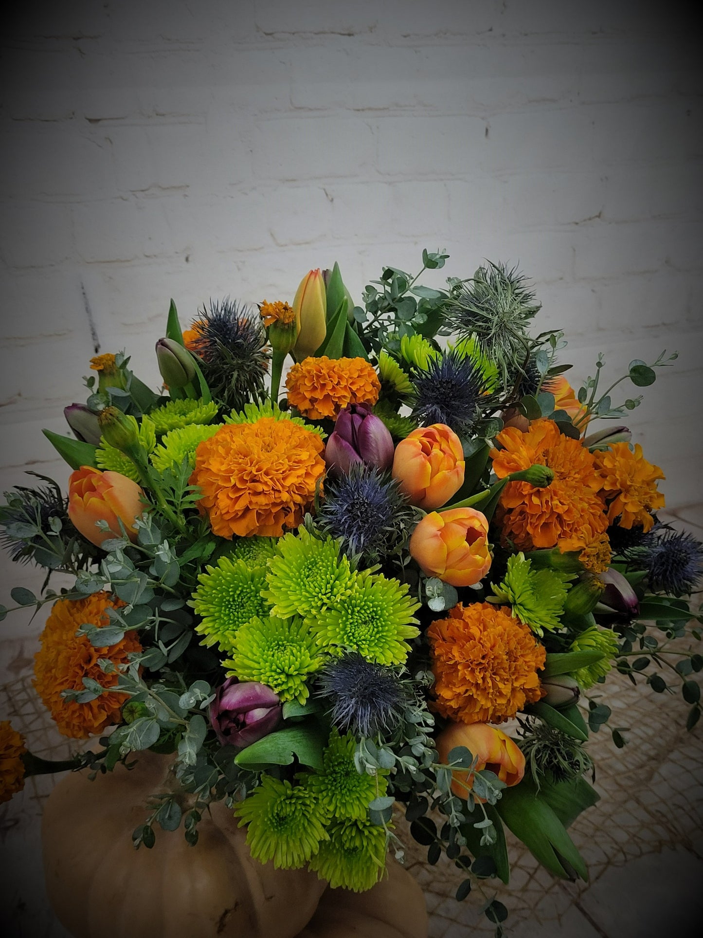 Orange, green and blue mixed bouquet with seasonal flowers