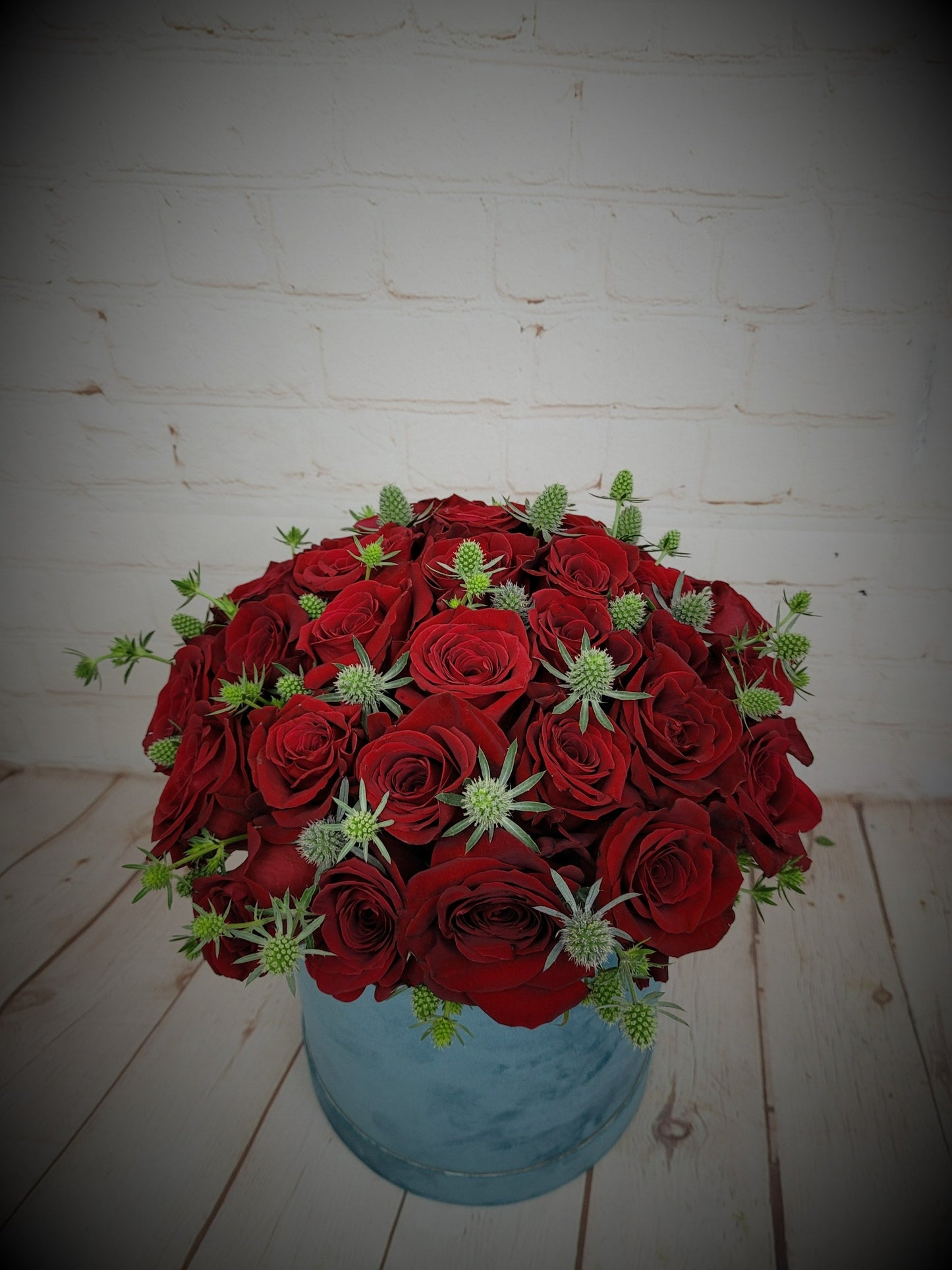 Red roses and blue eryngium in blue box